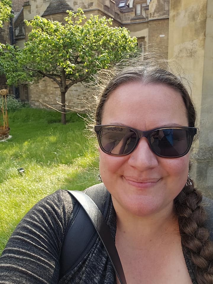 Lindsay smiles for the camera with a tree in the background.