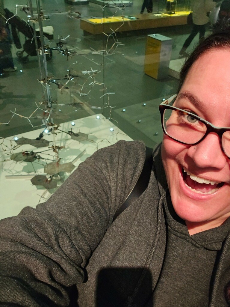 Lindsay smiles for the camera as she stands in front of a model.